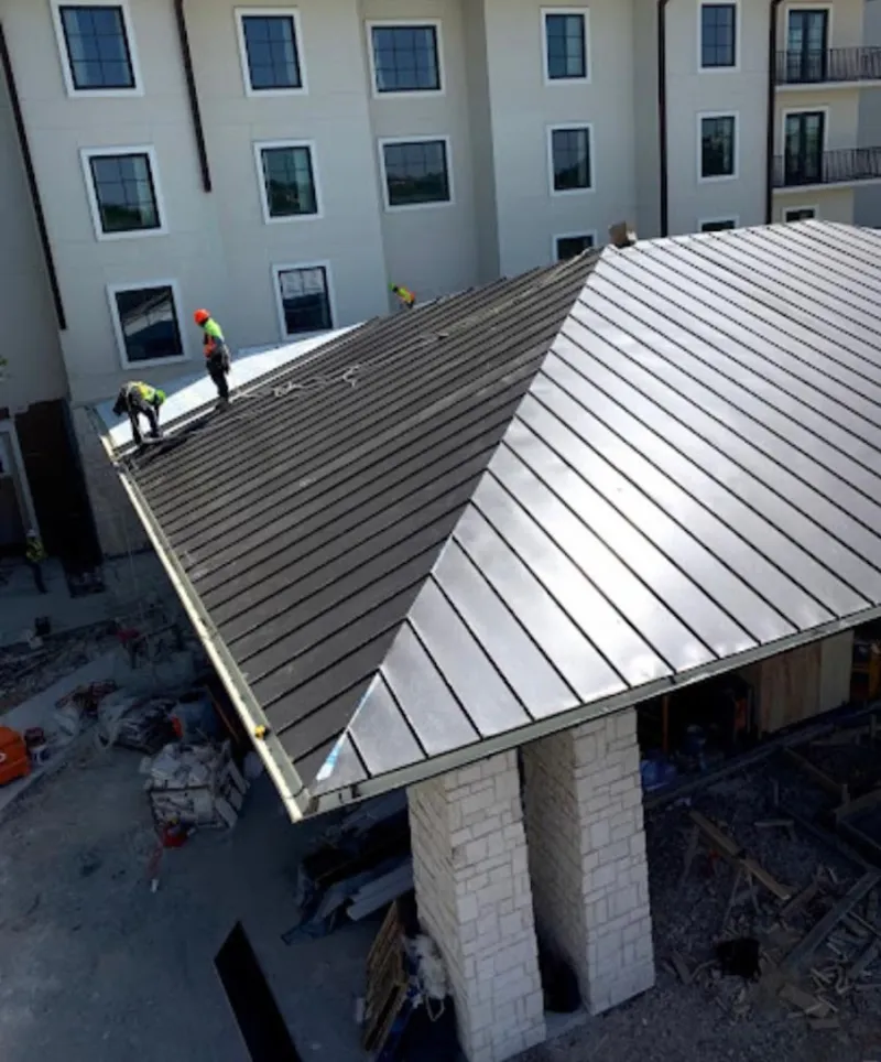 Crew installing standing seam metal roof panels on a commercial project in Weatherford